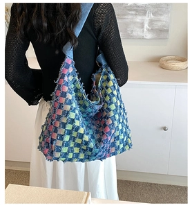 Detail of colorful patchwork denim tote bag worn by a model in a minimalist room