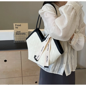 Detail view of cream tote bag with contrast black trim and stylish V-shape opening