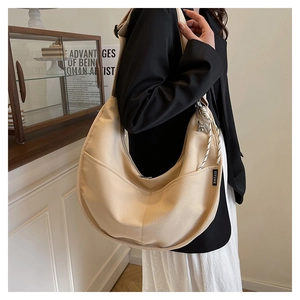 Close-up of beige canvas hobo bag with zipper closure and adjustable strap details