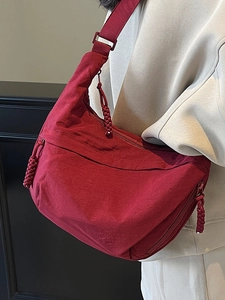 Minimalist burgundy crescent bag for women featuring a woven zipper and wide strap