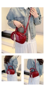Close-up of a glossy deep red bowling bag with elegant rope tassel detail and shoulder strap