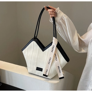 Close-up of contrast color tote bag with white vertical texture and black leather handle