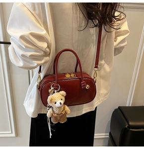 Close-up of dark red Boston bag in glossy faux leather with a cute bear plush charm