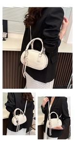 Detail of glossy cream leather bowling bag featuring woven charm and thin strap
