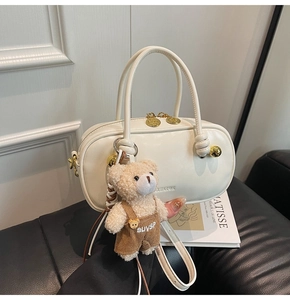 Detail of cream Boston bag with plush bear charm and adjustable crossbody strap