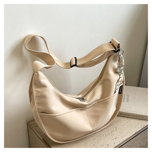 Detailed macro view of the beige hobo bag with adjustable strap and decorative pendant