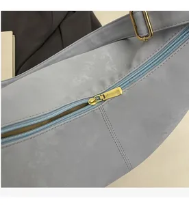 Detail of smooth gold metal zipper and soft light blue textured fabric on a tote bag