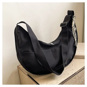 Detail shot of black nylon crescent bag with wide shoulder strap and brand pendant