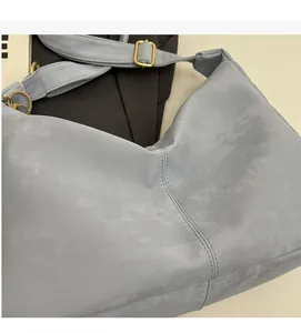 Detail shot of the soft light blue tote bag showing the matte texture and golden hardware