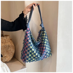 Detail of colorful woven tote bag featuring frayed edges and blue denim handles