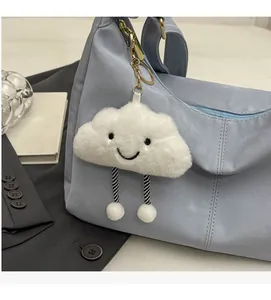 Detail of a white fluffy cloud pendant with a smiling face on a blue nylon tote bag