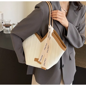Close-up of contrast-colored tote bag with textured stripes and leather trim accents