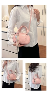 Detail of pink glossy patent leather bowling bag with blue heart charm and tassels