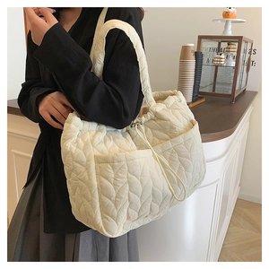 Quilted cream tote bag with wheat pattern stitching and drawstring in a cafe setting