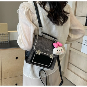 Detail of a chic patchwork mini backpack featuring star rivets and a cute plush bunny charm