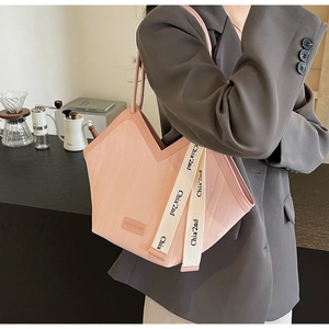Detail view of pink tote bag with V-shaped opening and woven strap in a cafe setting