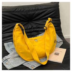 Detailed macro view of yellow canvas crescent bag with double zipper and wide strap