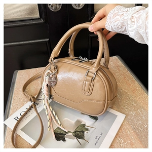 Detail view of smooth apricot Boston bag with heart charm and glossy vintage texture