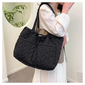 Detail view of the black quilted tote bag with leaf pattern stitching and drawstring closure