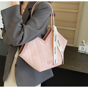 Detail of pink tote bag showing V-shaped opening and wavy texture with ribbon