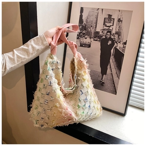 Close-up of colorful woven denim tote bag with frayed fringe texture and pink knotted handle