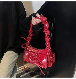 Dettaglio borsa a tracolla in pelle verniciata rossa con pieghe e decorazione a fiocco