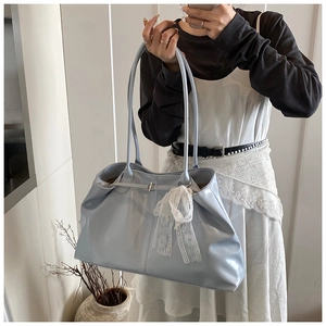 Detail of light blue tote bag with white lace bow charm and elegant long shoulder straps