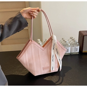 Detail of pink tote bag with wavy texture, white lettered ribbon and leather brand tag