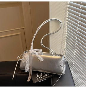Detail of silver metallic bag featuring white lace ribbon and delicate bow accents