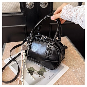 Detail of a black glossy patent leather mini bowling bag with heart charm and silver metal