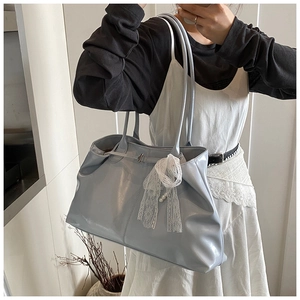 Detail of light blue large tote bag featuring a decorative white lace bow on the front