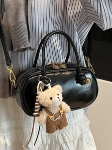 Glossy black Boston handbag with golden hardware and a cute teddy bear plush charm