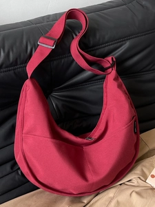 Minimalist burgundy half-moon canvas shoulder bag with adjustable wide strap and zipper