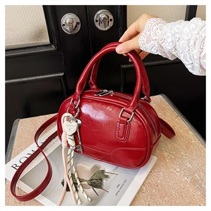 Macro detail of red patent leather bowling bag with heart lock charm and silver hardware