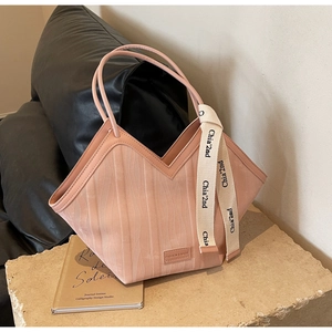 Detail of peach tote bag showing V-shaped opening and vertical ripple texture pattern