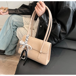 Détail du sac à bandoulière abricot avec finition brillante et foulard sur le mannequin