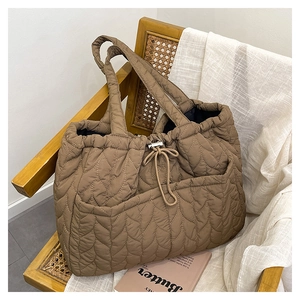 Detail of coffee brown quilted tote bag with heart patterns and drawstring bow on a chair