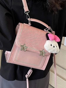Pink crossbody square bag with star buckles and plush pendant shown on model