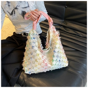 Close-up of colorful woven hobo bag with fringe edges and knotted pink handle