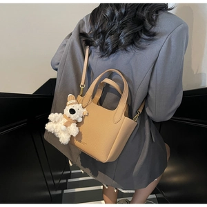 Litchi pattern leather bucket bag in camel with a cute white plush bear pendant detail