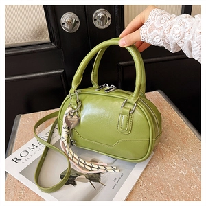 Close-up of green shiny leather bowling bag with heart lock and tassel charm detail
