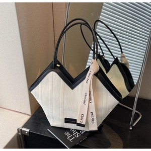 Detailed close-up of a striped tote bag with leather trim and fashion brand labels