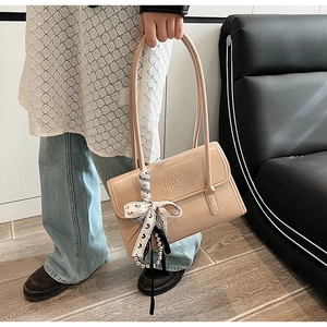 Détail du sac beige minimaliste avec nœud à motif cœur et pendentif en perles élégant