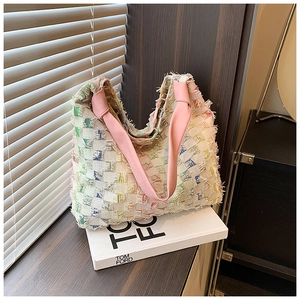 Detail of multi-color tweed tote bag with frayed edges and pink shoulder strap