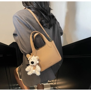 Litchi pattern camel leather bucket bag with plush bear charm on model's back