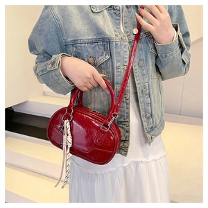 Detail of red glossy patent leather bowling bag with braided charm on the handle