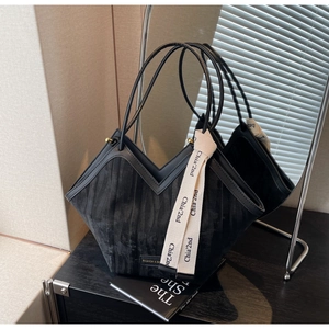 Detailed close-up of a black tote bag with V-shaped opening and brand ribbon detail