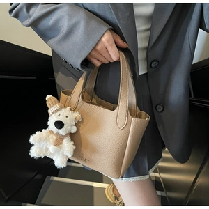 Detail of lychee pattern leather bucket bag with cute plush dog charm and short handle