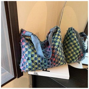 Detail of colorful plaid tote bag featuring raw frayed edges and blue denim handle