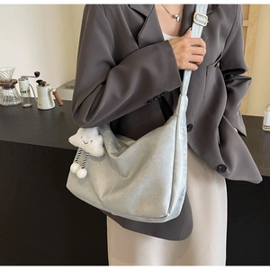 Detail of silver faux leather tote bag with adjustable strap and plush cloud charm